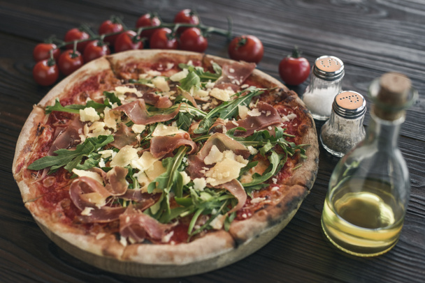 Concentration sélective des pizzas italiennes, tomates cerises, épices et huile d'olive sur table en bois
 - Photo, image