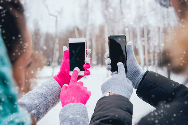 Couple using smartphone with gloves for touch screens in winter - Fotó, kép