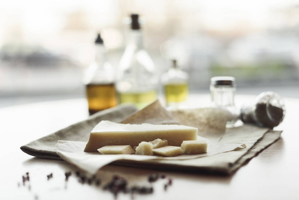 selective focus of piece of cheese on napkin and oil in bottles  - Фото, зображення