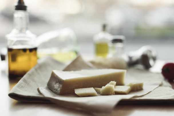 selective focus of piece of cheese on napkin and oil in bottles  - Foto, Imagem