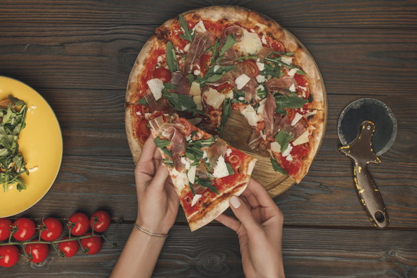 częściowy widok kobiecych rąk i domowe włoskiej pizzy na powierzchni drewnianych - Zdjęcie, obraz