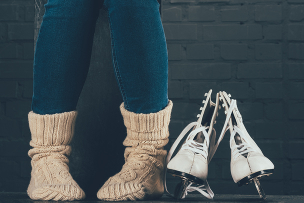 cropped image of woman sitting in warm socks, figure skates on floor - Photo, Image