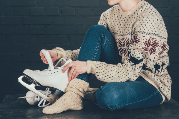 cropped image of woman sitting on gray floor and wearing white skates - Foto, Imagem