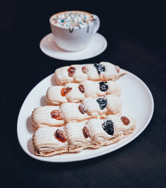French meringue cookies on white plate on dark surface, closeup, selective focus - Fotó, kép