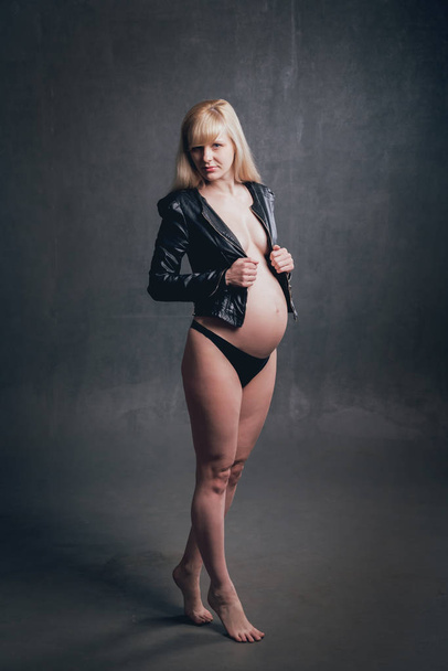 Studio picture of beautiful nude pregnant woman in leather jacket - Fotoğraf, Görsel