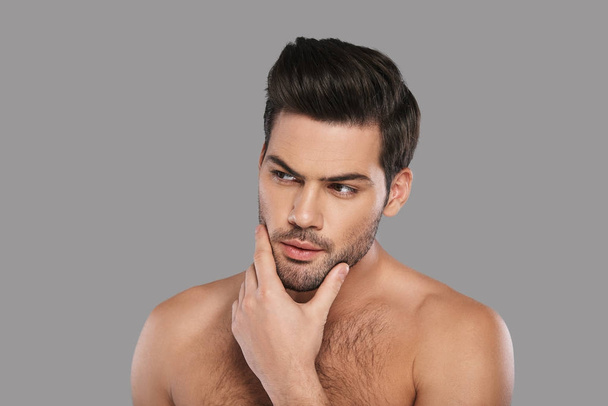 shirtless thoughtful brunette man looking away and keeping hand on chin  - Foto, immagini