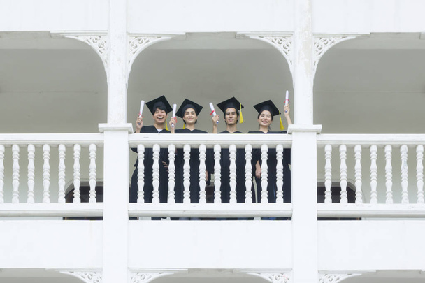 students in feeling happy with graduation gowns stand at corrido - Fotoğraf, Görsel