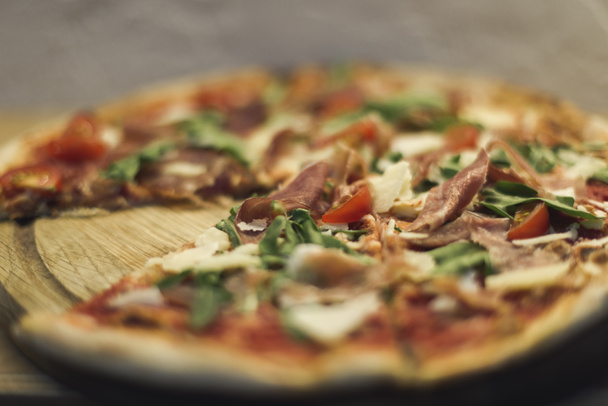 selective focus of tasty homemade italian pizza on wooden board - Фото, изображение