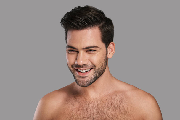shirtless handsome young smiling man looking away against grey background - Fotoğraf, Görsel