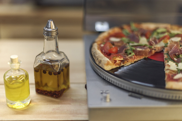 close up view of types of oil in bottles and italian pizza on vinyl record player - Φωτογραφία, εικόνα