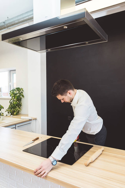 a successful young man in a suit measures the width of a kitchen countertop - Zdjęcie, obraz