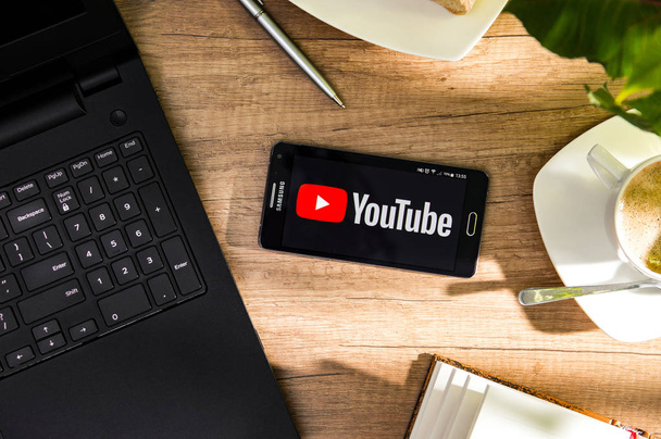 Samsung A5 is laying on the desk with YouTube logo on screen. - Valokuva, kuva