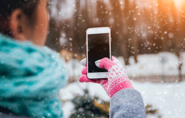 Woman using smartphone with pink gloves for touch screens in winter. - Foto, imagen