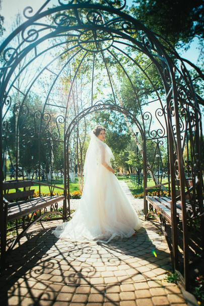 Young beautiful bride standing in a park gazebo. - Photo, image