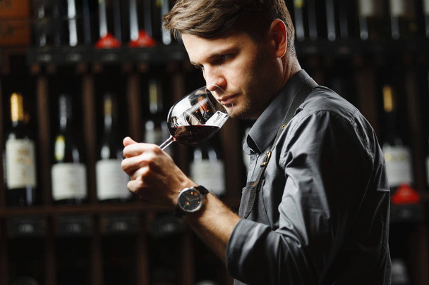Bokal of red wine on background, male sommelier appreciating drink - Fotó, kép