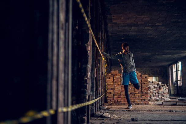 portrait of motivated afro-american man training in abandoned hangar place with earphones - Photo, Image