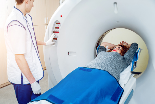 Attrezzature mediche. Maschio medico caucasico e paziente femminile in camera di tomografia computerizzata in ospedale
. - Foto, immagini