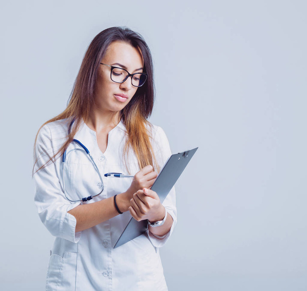 Young nurse or doctor in glasses with stethoscope against white wall - Foto, Imagem