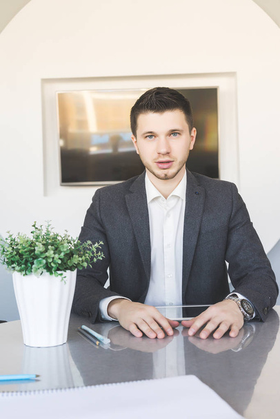 giovane uomo fiducioso di successo in giacca e cravatta seduto in ufficio a tavola
 - Foto, immagini