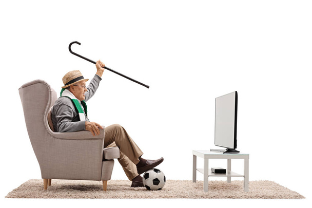 soccer fan in an armchair watching television - Фото, изображение