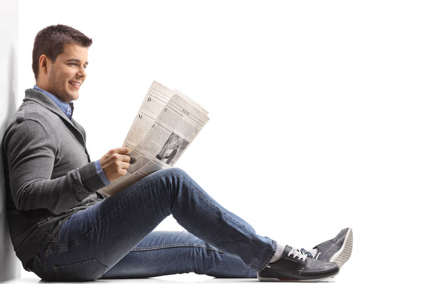 man seated on the floor reading a newspaper - Valokuva, kuva