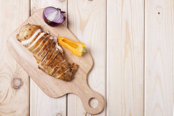 Filetes de pollo a la parrilla sobre tabla de madera con cebolla, pimienta. Copiar espacio. Menú maqueta
 - Foto, Imagen