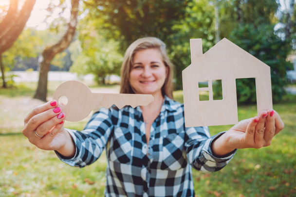 Young woman holding model of house at her hands. Outdoors. Summertime. Real estate and property concept - Foto, imagen