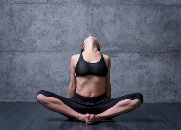 Woman practising yoga at grey wall. - Фото, изображение