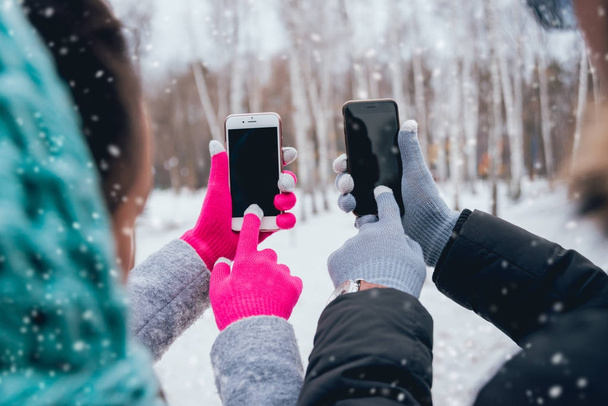 Couple using smartphone with gloves for touch screens in winter - Foto, Bild