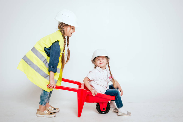 Две маленькие веселые девочки с косичками играют в ремонте или строительстве на белом
 - Фото, изображение
