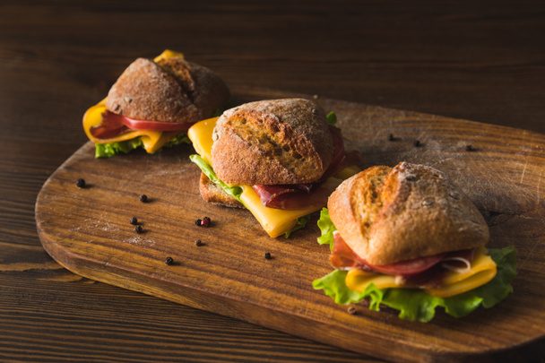 three sandwiches with cheese and vegetables on cutting board - Fotografie, Obrázek