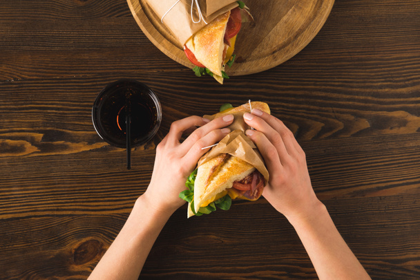 обрезанный образ женщины, держащей в руках сэндвич
 - Фото, изображение