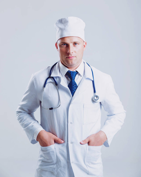 Adult caucasian blue eyed doctor posing with different medical things before white wall with copy space - Foto, imagen