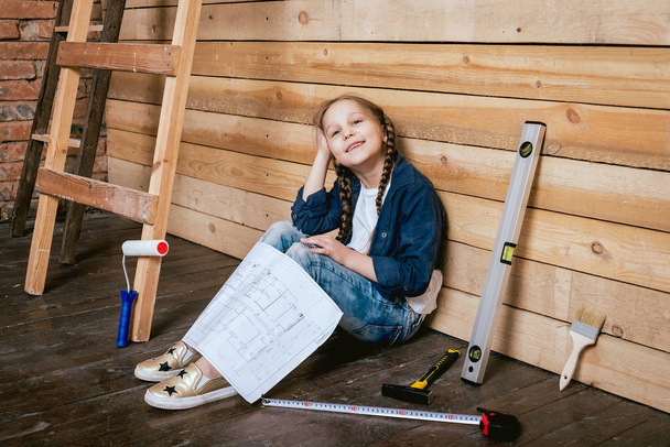 Pequena menina alegre com tranças jogando em reparação ou construção
 - Foto, Imagem