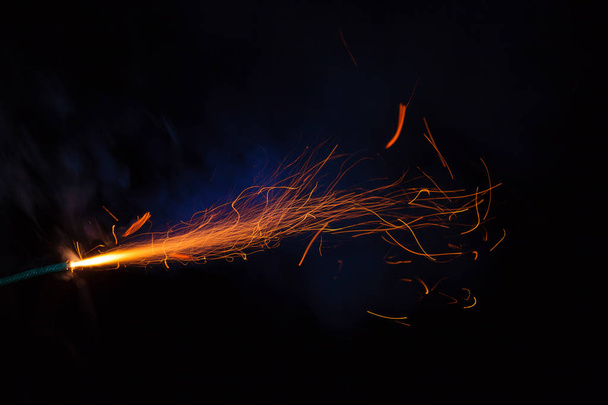 Fusible ardiente con chispas y humo azul sobre fondo negro
 - Foto, imagen
