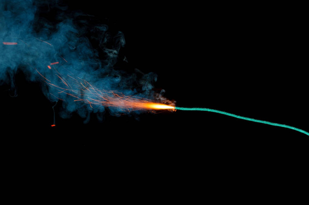 Fusible ardiente con chispas y humo azul aislado sobre fondo negro
 - Foto, Imagen