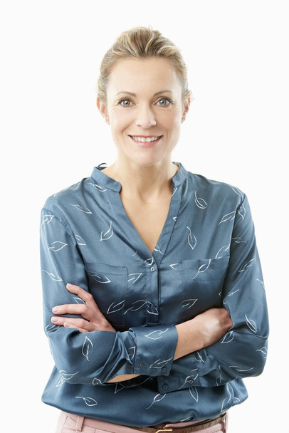 Smiling beautiful middle aged woman standing with arms crossed at isolated white background.  - 写真・画像