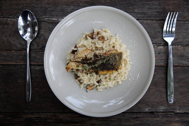Risotto z stek filet z okonia morskiego na podłoże drewniane, włoskie jedzenie  - Zdjęcie, obraz