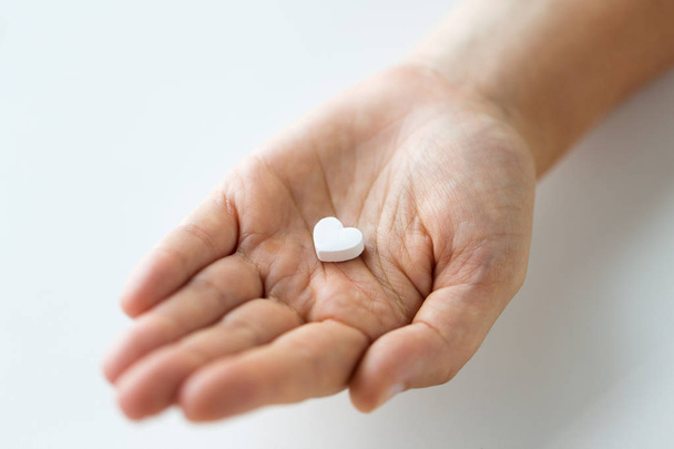 close up of hand holding medicine heart pill - Fotoğraf, Görsel
