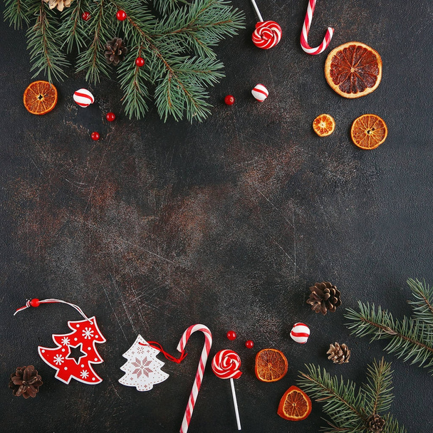 Christmas attributes. Caramelized oranges, fir branches and candy cane on dark background, Selective focus - Foto, Bild
