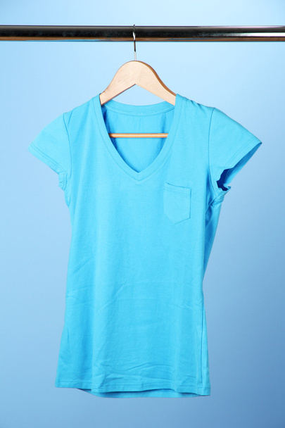 T-shirt on wooden hanger, on blue background - Fotografie, Obrázek