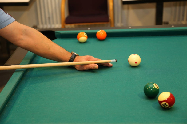Biljartballen op groene tafel en hand met biljart keu - Foto, afbeelding