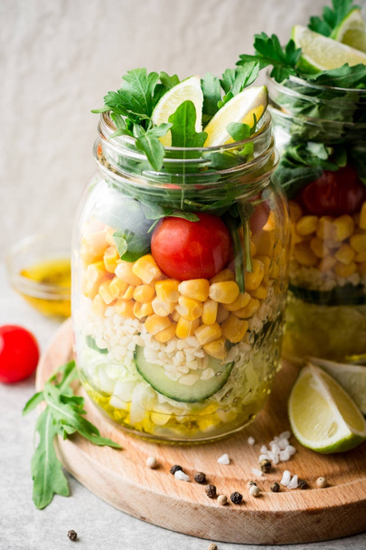 Healthy homemade salads with bulgur, vegetables and lime in mason jars on grey stone background. - 写真・画像
