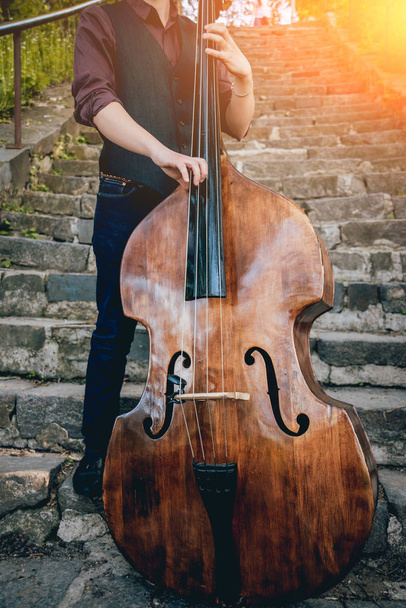 Cropped image of musician playing contrabass at the street. - Zdjęcie, obraz