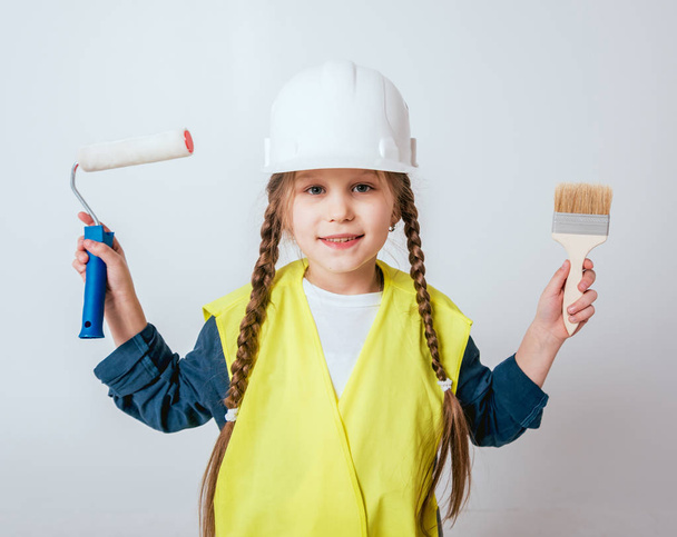 Little cheerful girl with braids playing in repair or construction - Foto, imagen