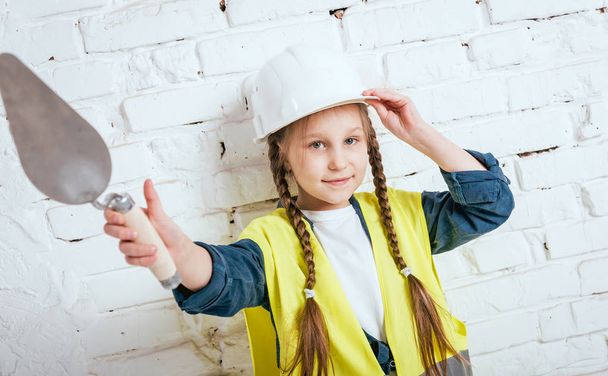 Little cheerful girl with braids playing in repair or construction - Фото, изображение