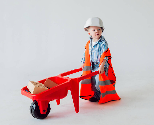 Little boy with wheelbarrow on the white background. Construction, repair, interior. - Фото, изображение
