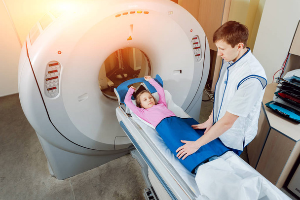 Attrezzature mediche. Maschio medico caucasico e paziente bambina in camera di tomografia computerizzata in ospedale
. - Foto, immagini