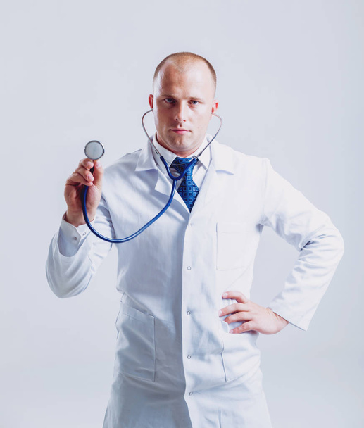 Adult caucasian blue eyed doctor posing with different medical things before white wall with copy space - Фото, изображение