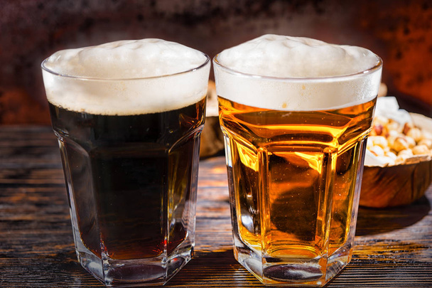 Two glasses with freshly poured dark and light beer near plate w - Foto, afbeelding